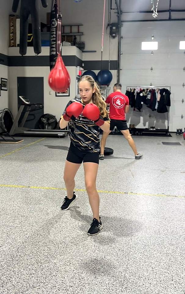 Une jeune en position de garde avec des gants rouges