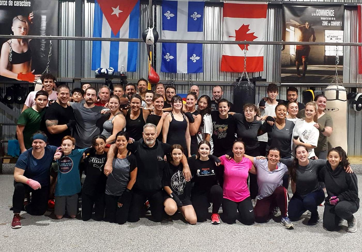 Membres du club réunis après un cours, devant les drapeaux du gym
