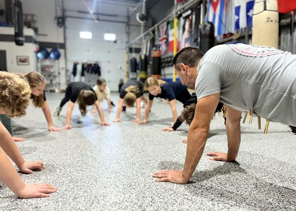 Un entraîneur et des enfants en position de planche dans le gym